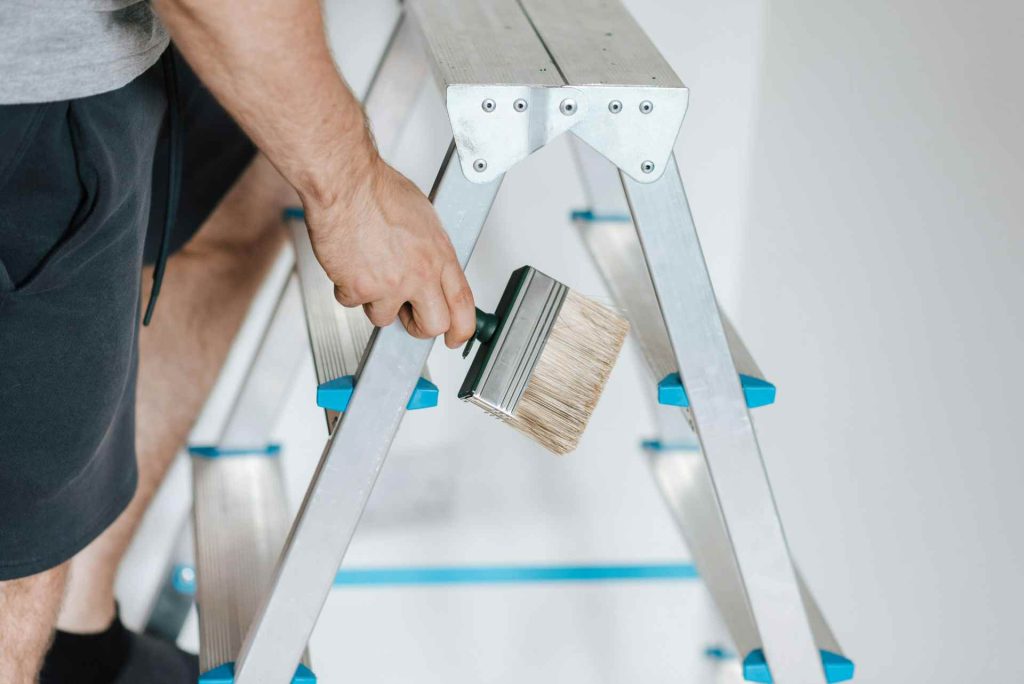 Person painting from a ladder