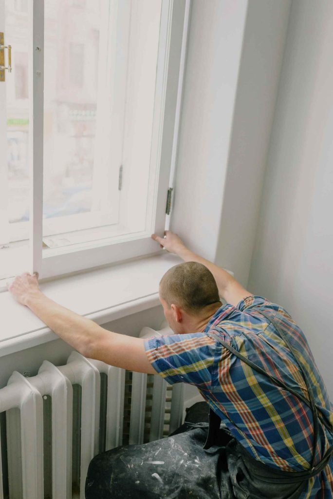 man adjusting wooden window frame